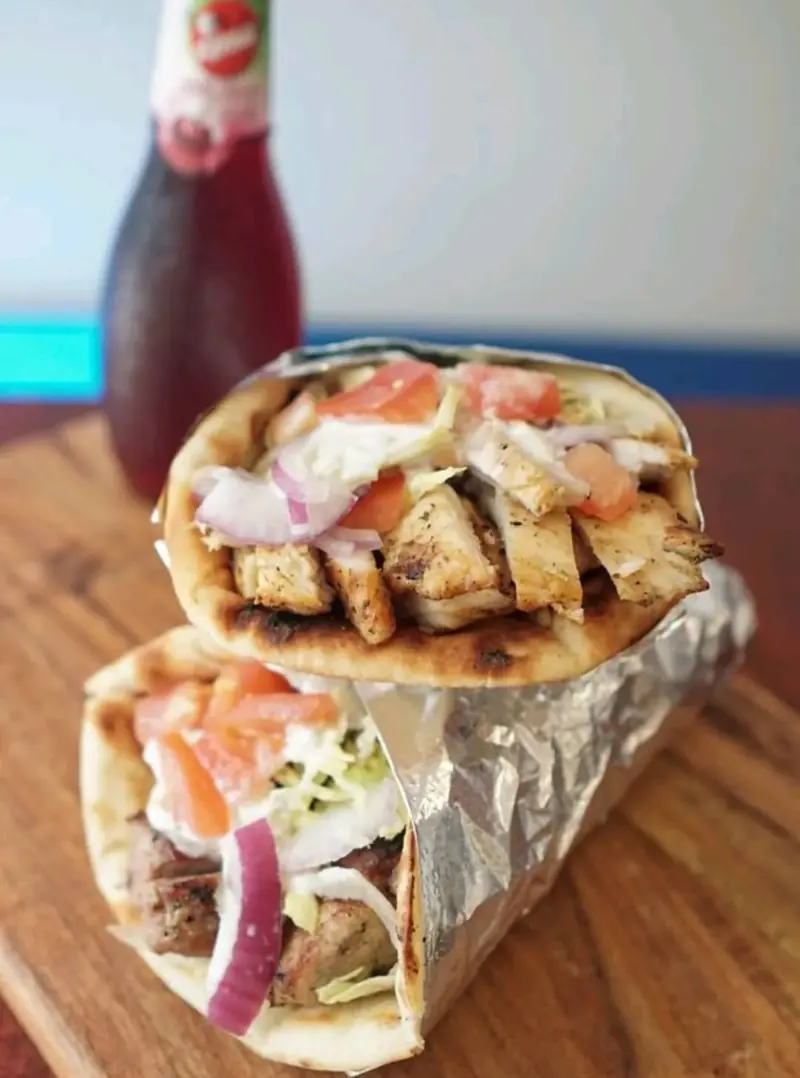 Chicken pita wrapped in foil on a wooden board