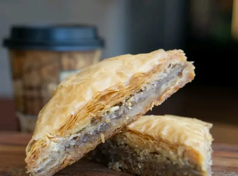 A golden filo pastry beside a coffee