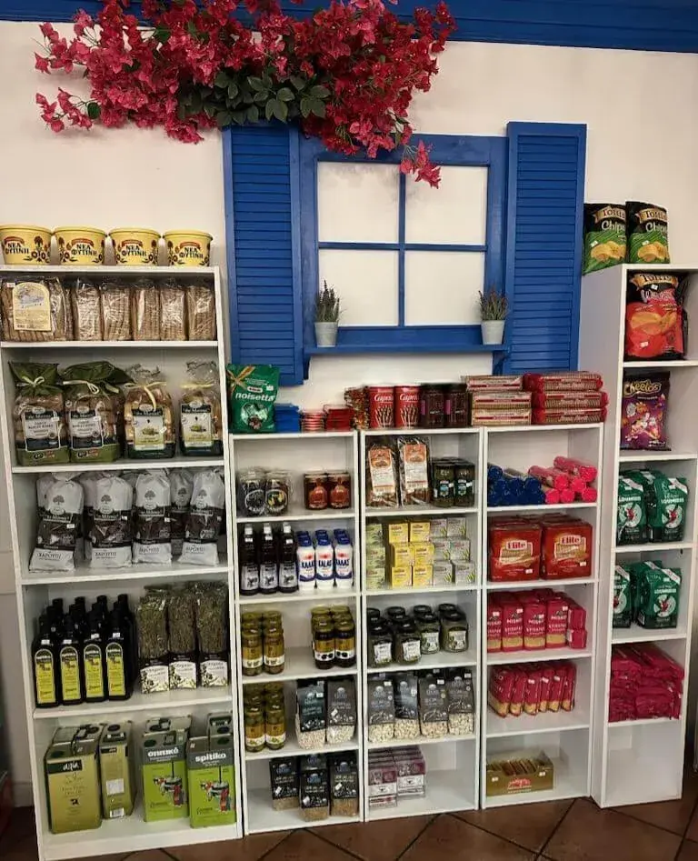 Market shelves under a blue shuttered window with bougainvillea above