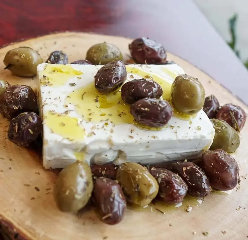 A slab of feta with Kalamata and green olives and oregano